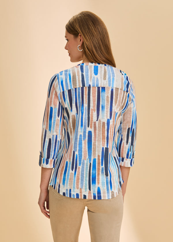 Woman wearing a colorful patterned shirt against a beige background