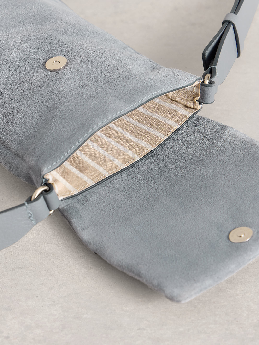 Gray suede handbag with beige interior on a light gray background
