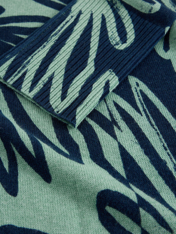 Close-up of a fabric with a leaf pattern in green and blue.