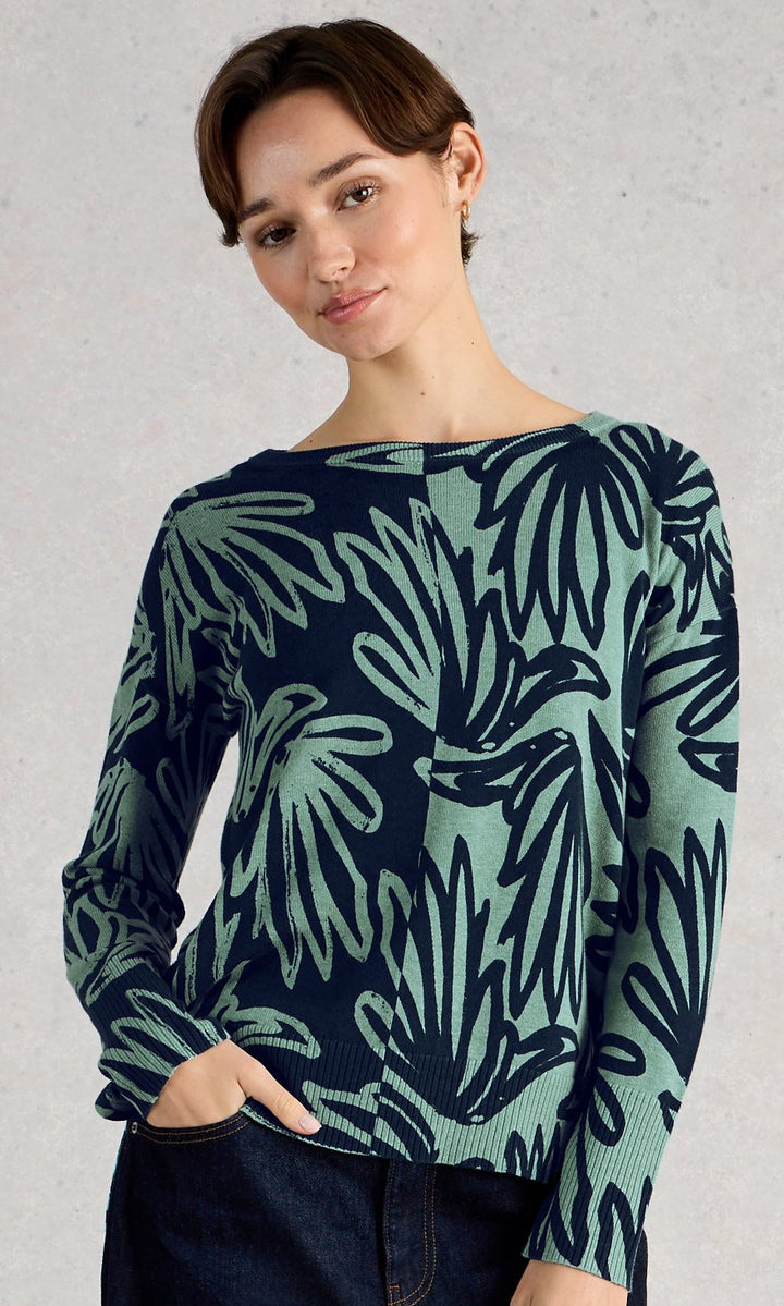 Woman wearing a navy sweater with green leaf pattern against a gray background