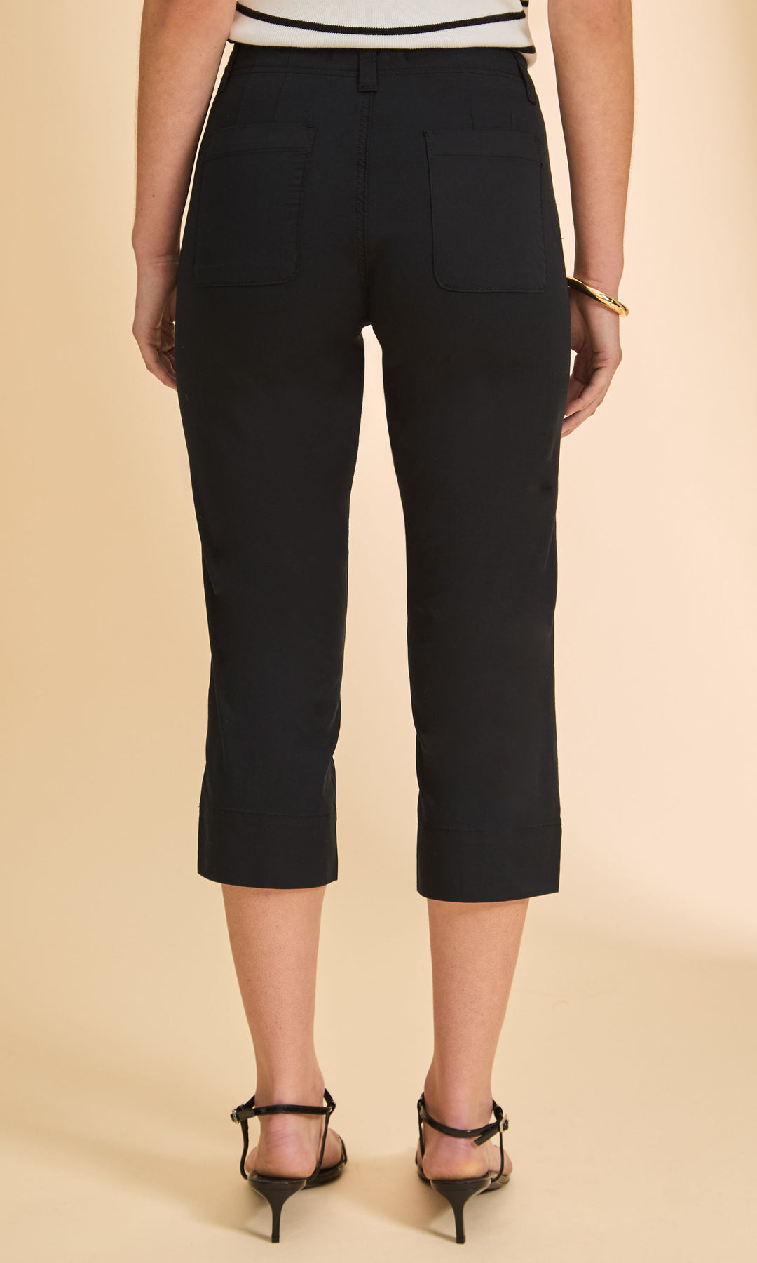 Person wearing black capri pants on a beige background