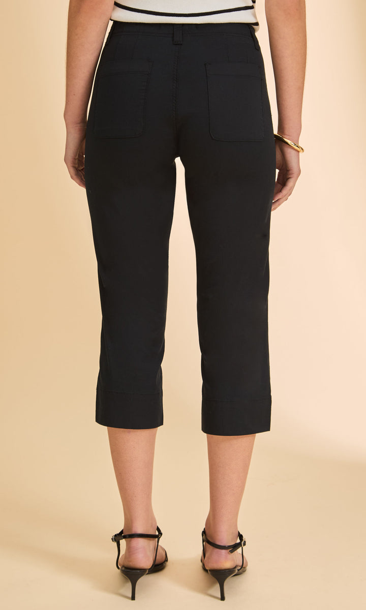 Person wearing black capri pants on a beige background