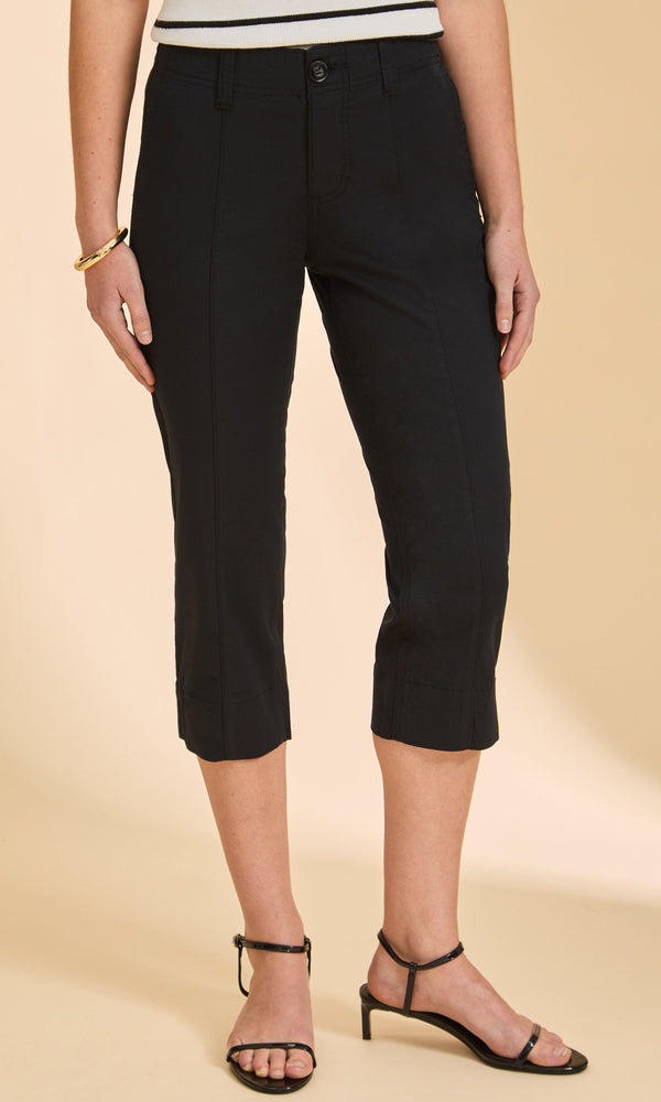 Person wearing black capri pants on a beige background