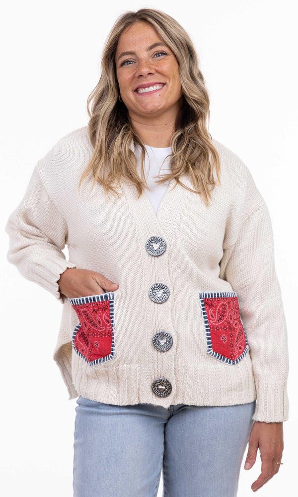 Beige knit button-front cardigan with red bandana pockets and a denim flower patch on the back