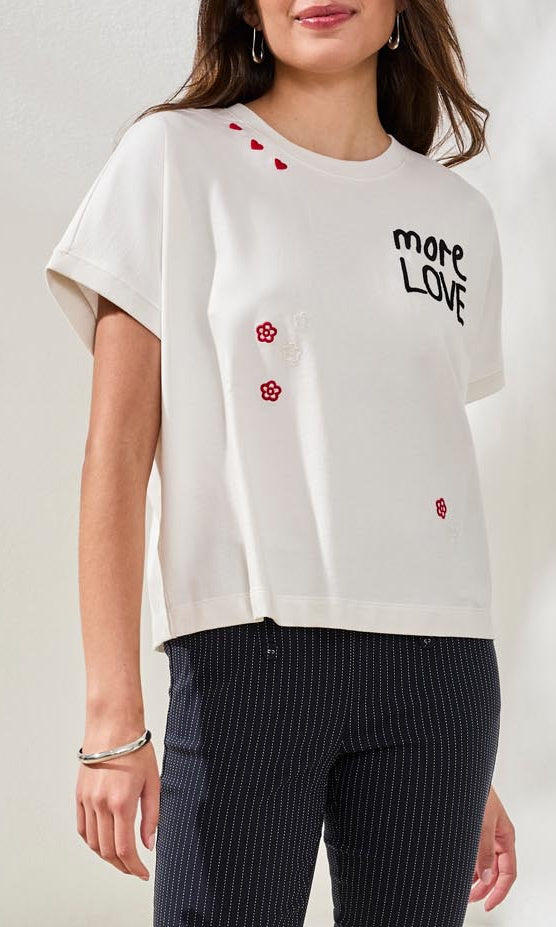 Woman wearing a white t-shirt with text and red heart designs on a plain background