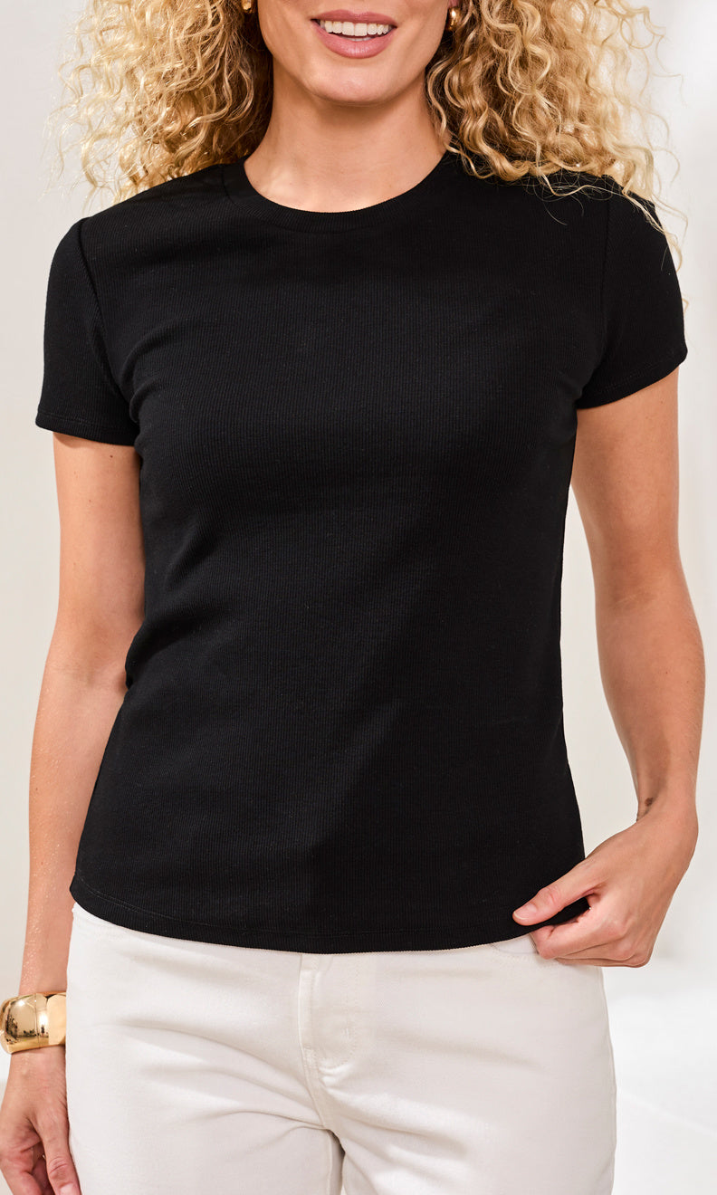 Woman wearing a black t-shirt and white pants against a plain background