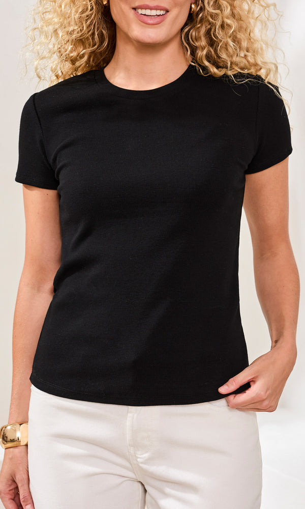 Woman wearing a black t-shirt and white pants against a plain background