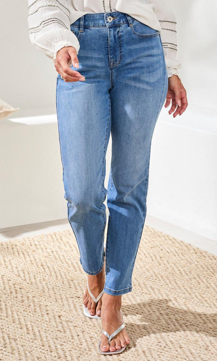 Person wearing light blue jeans on a neutral background