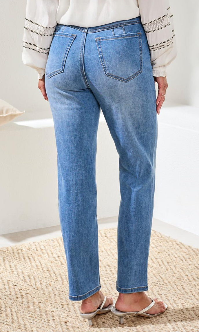 Person wearing blue jeans and a white top on a neutral background