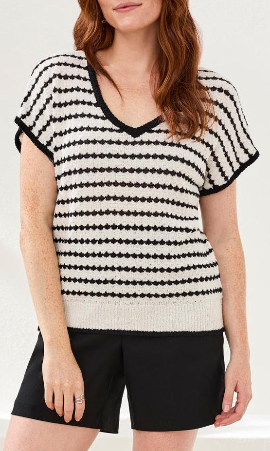 Woman wearing a black and white striped sweater with a plain background