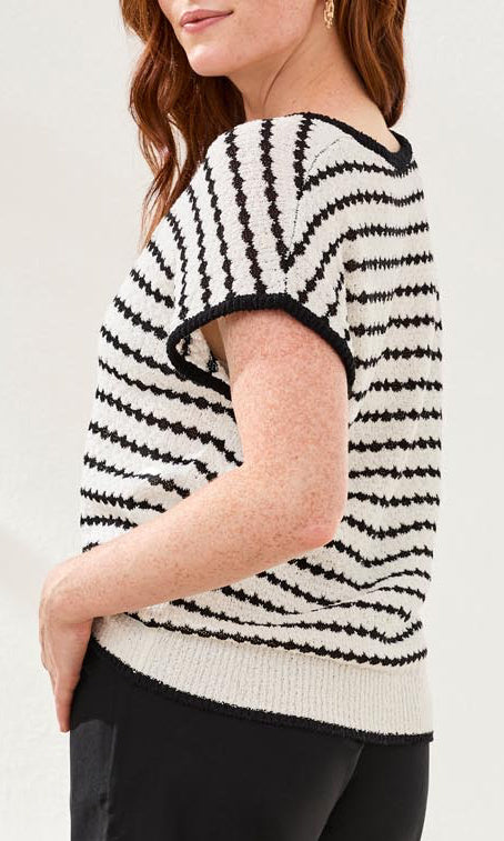 Woman wearing a black and white striped sweater against a plain background