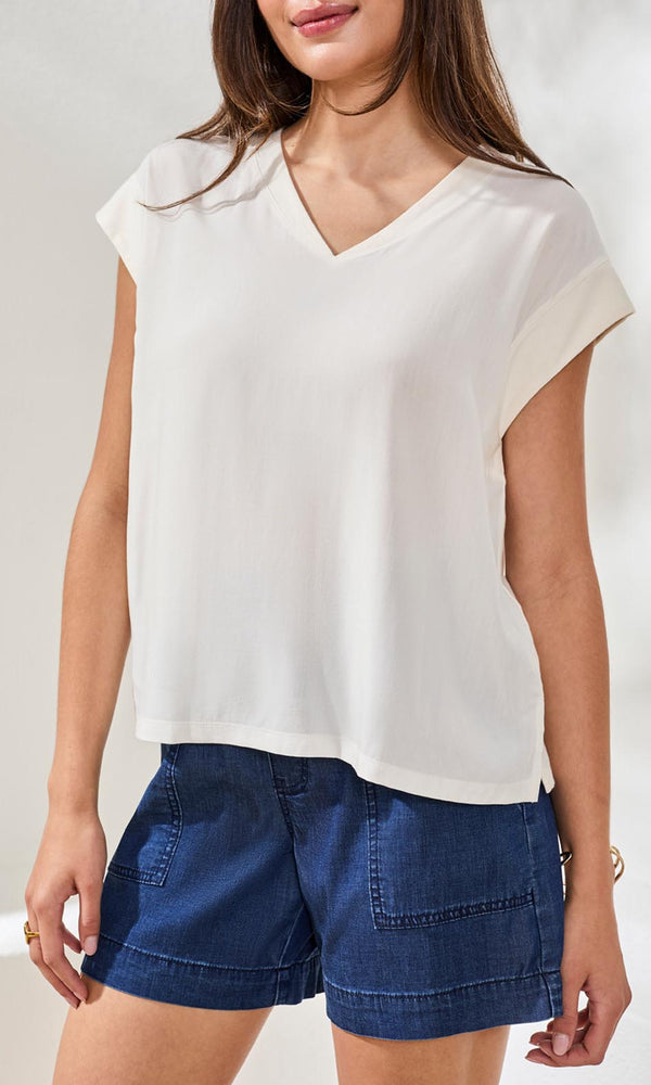 V-neck cap sleeve lightweight relaxed fit blouse with soft drape styled with denim shorts.