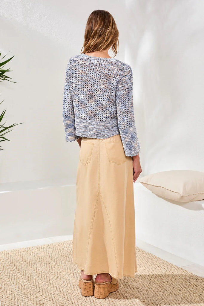 Woman wearing a textured sweater and beige pants in a minimal indoor setting