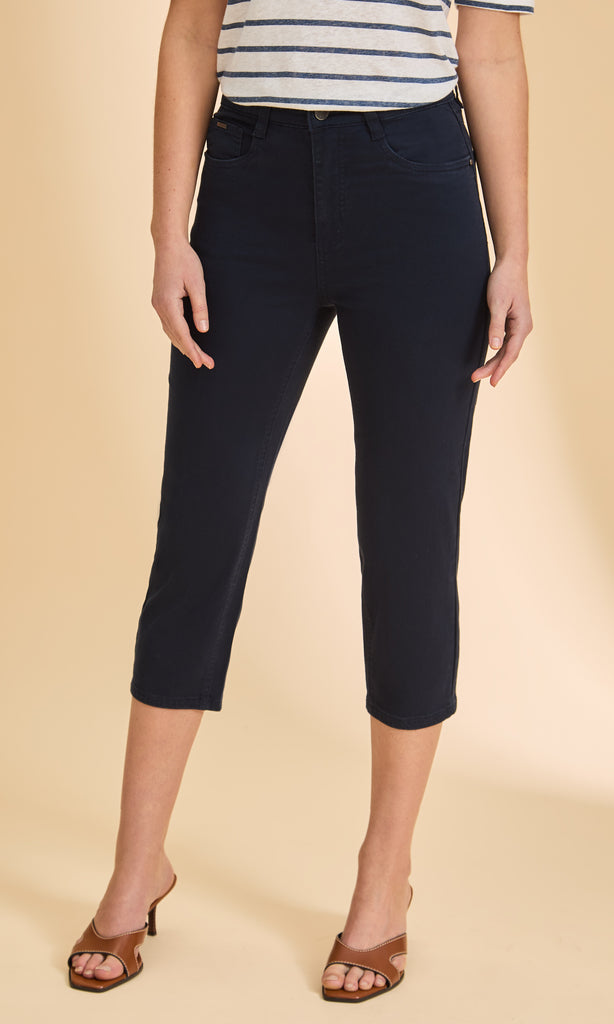 Person wearing navy capri pants on a beige background
