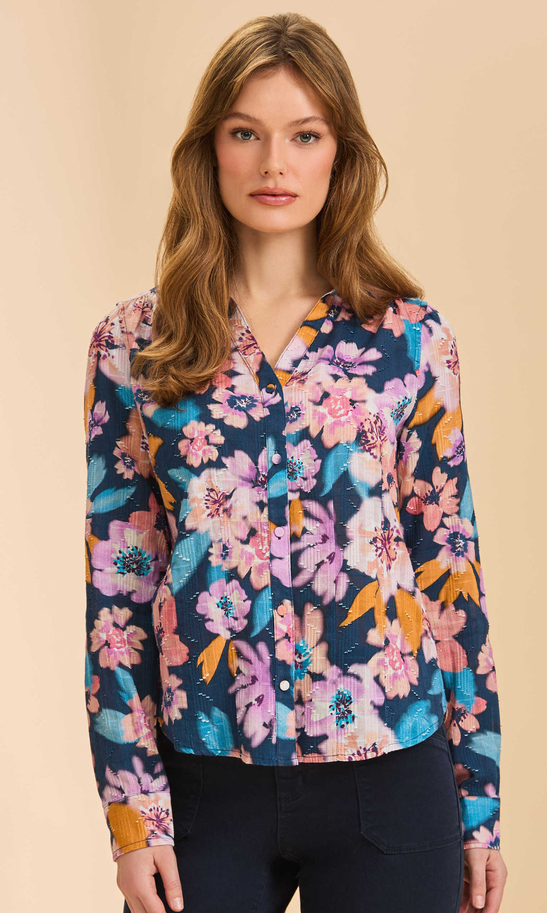 Woman wearing a colorful floral blouse against a beige background