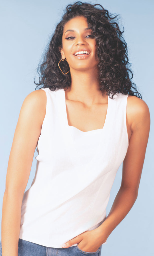 Woman wearing a white sleeveless top against a light blue background