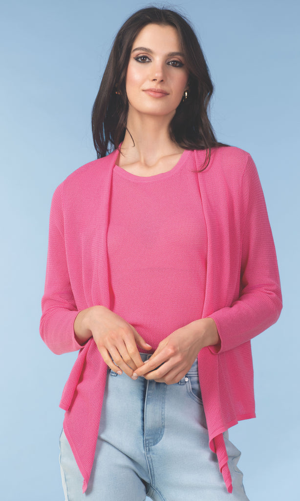 Woman wearing a pink cardigan over a pink top with light blue jeans on a light blue background