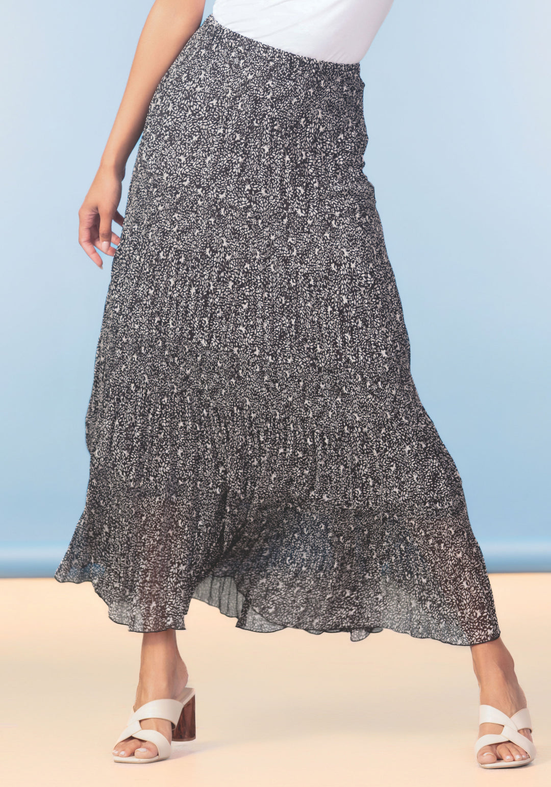 Person wearing a patterned skirt with a white top against a blue and beige background