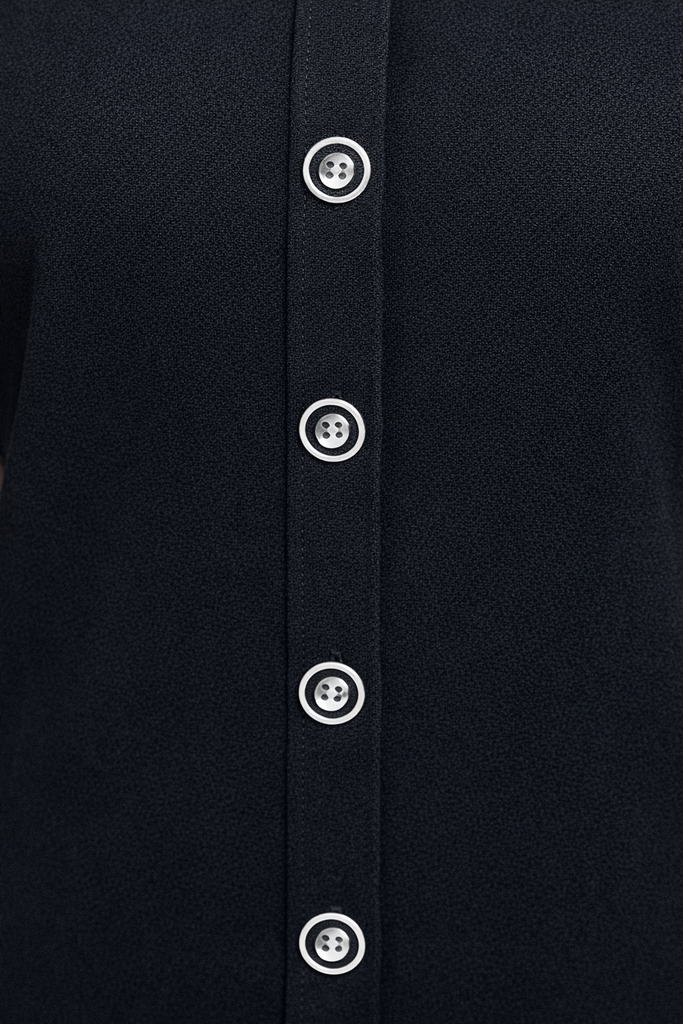 Close-up of a black shirt with white buttons on a dark background