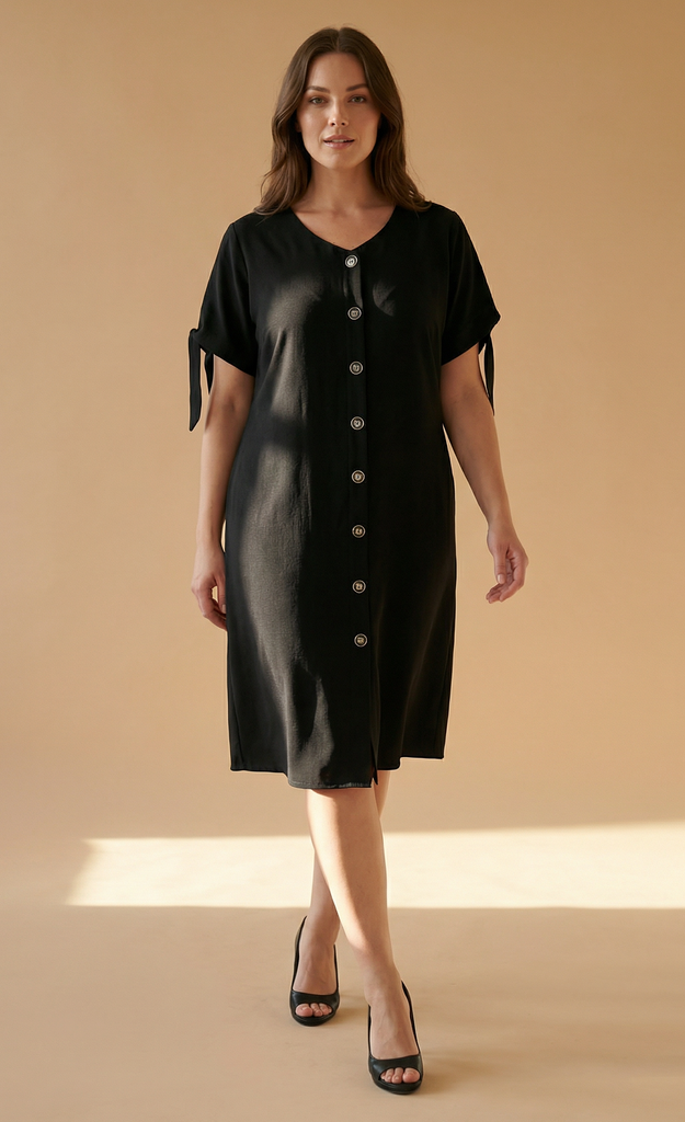 Woman wearing a black dress with button details on a beige background