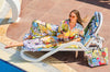 Woman in a colorful outfit lounging by a poolside with a drink.