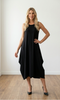 Woman wearing a black dress standing on a wooden floor with a white wall background