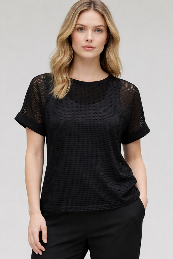 Woman wearing a black mesh top against a plain background