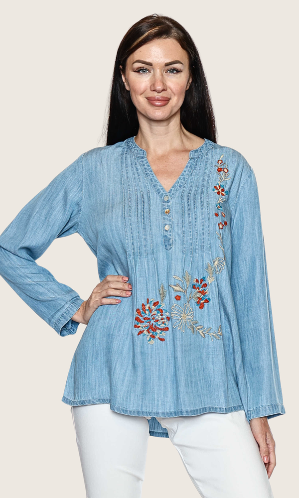 Woman wearing a blue denim blouse with floral embroidery on a beige background