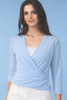 Woman wearing a light blue wrap-style top against a blue background