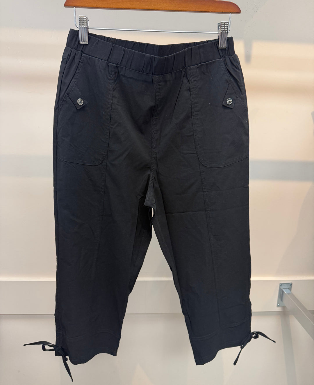 Black pants hanging on a rack against a white background