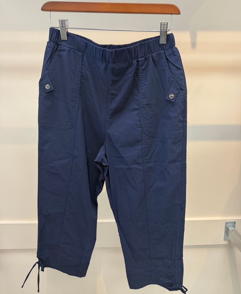 Pair of blue pants hanging on a rack against a white wall.