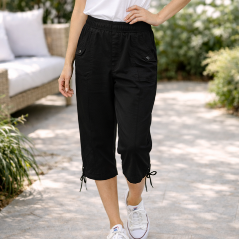 Person wearing black capri pants and white sneakers in an outdoor setting