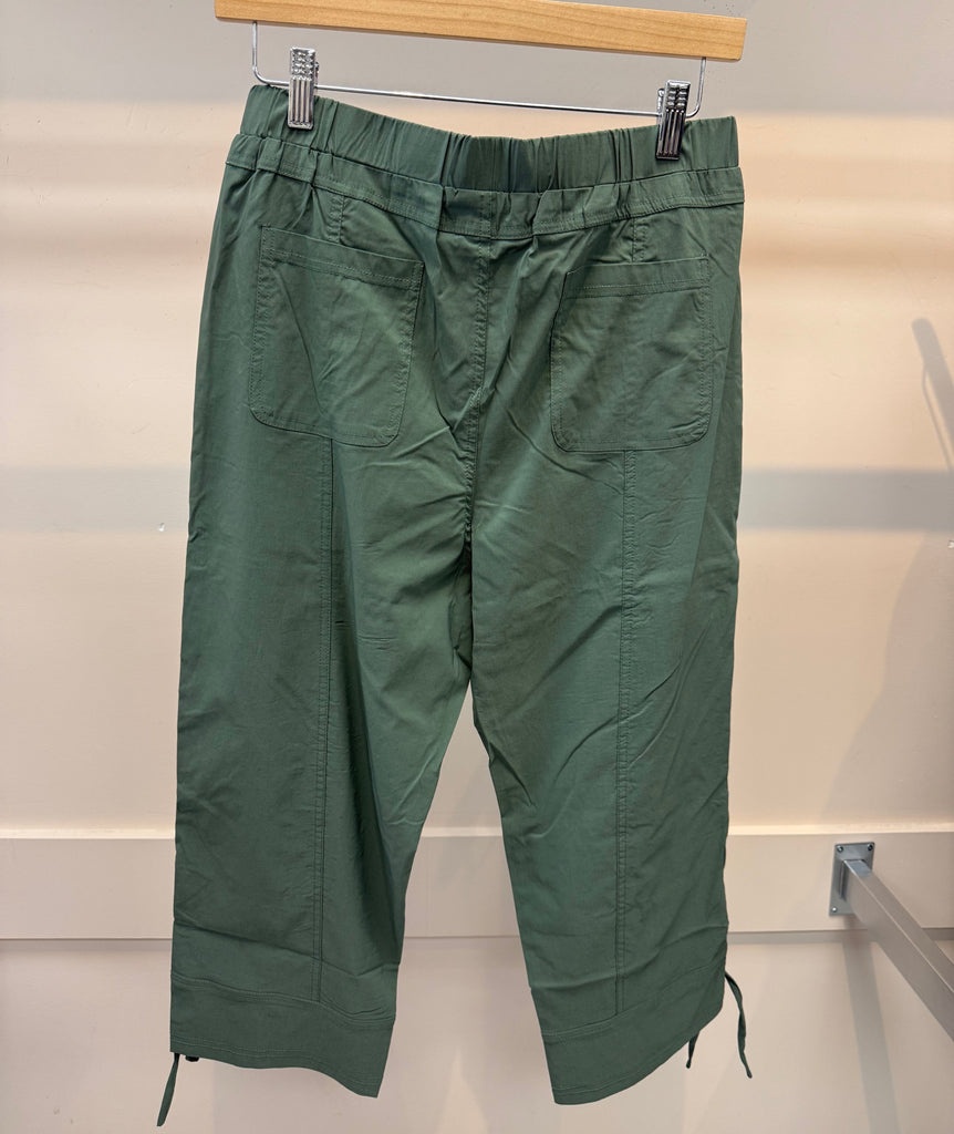 Green pants hanging on a rack against a white background