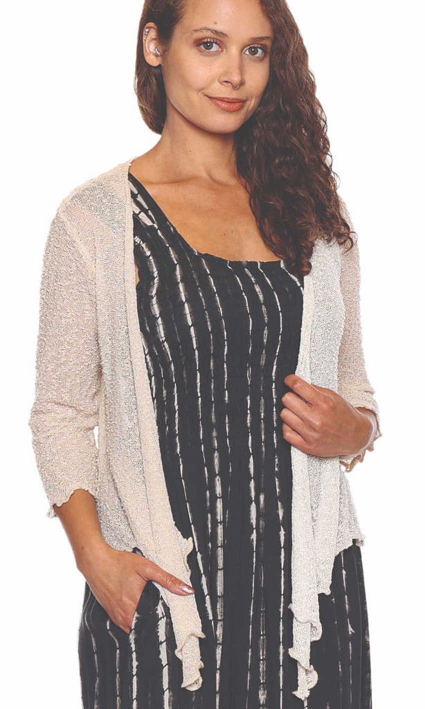 Woman wearing a black and white striped dress with a beige cardigan on a white background