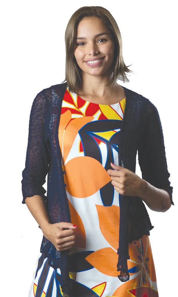Woman wearing a colorful dress with a black cardigan on a white background