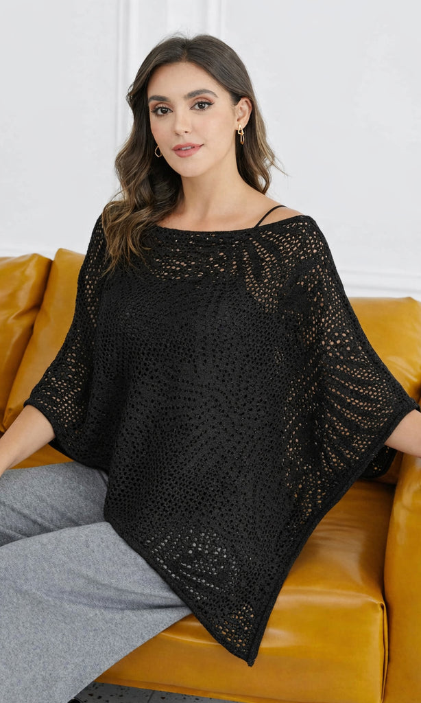 Woman wearing a black crochet poncho sitting on a yellow couch.