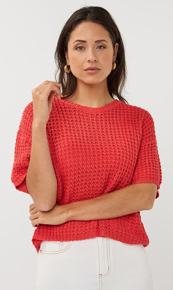 Woman wearing a red textured top against a white background