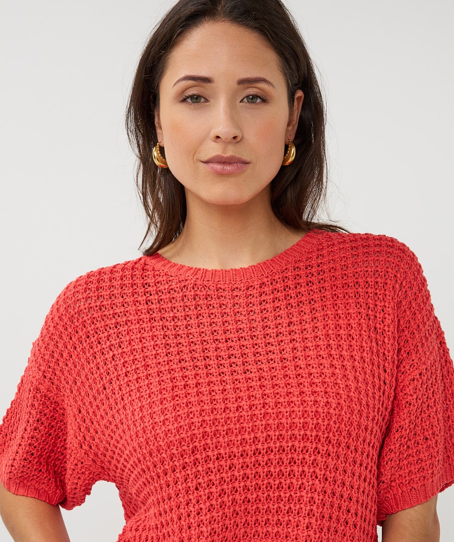 Woman wearing a red knitted sweater against a white background