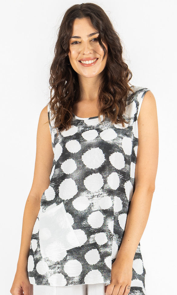 Woman wearing a sleeveless top with black and white abstract pattern on a plain background