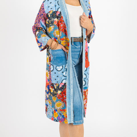 Woman wearing a colorful floral kimono over a white shirt and blue jeans on a white background