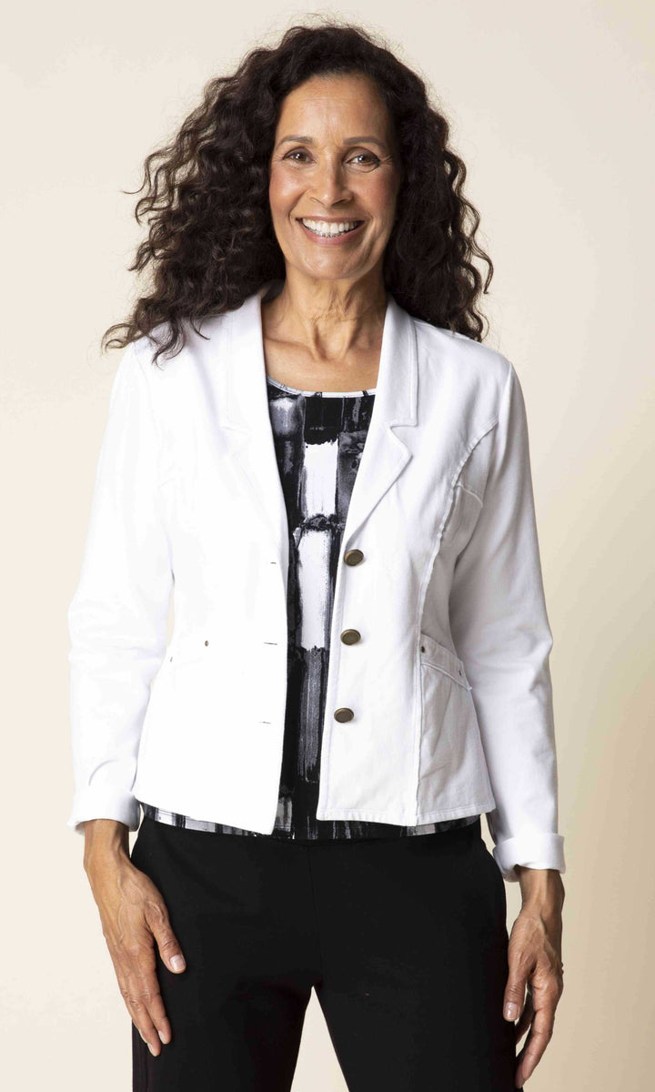 Woman wearing a white blazer over a patterned top on a beige background