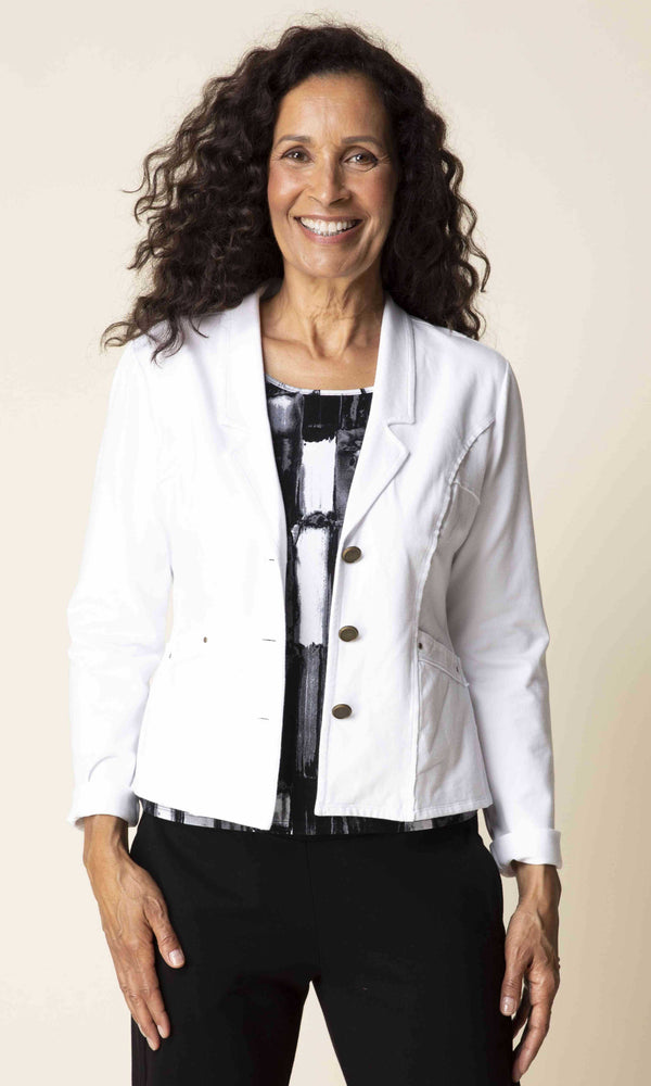 Woman wearing a white blazer over a patterned top on a beige background