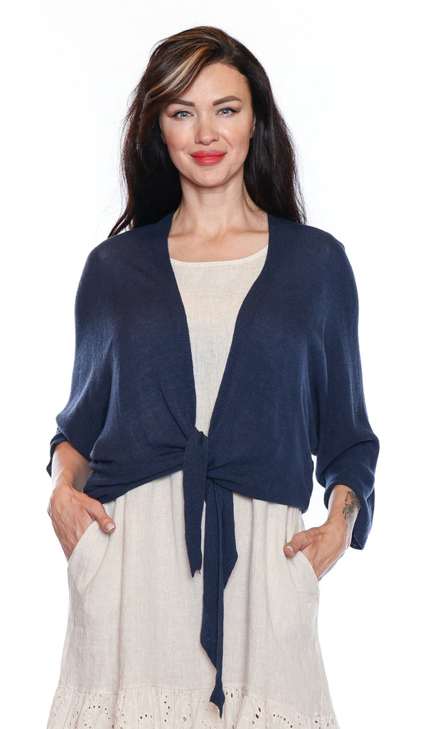 Woman wearing a navy blue cardigan over a white dress on a white background