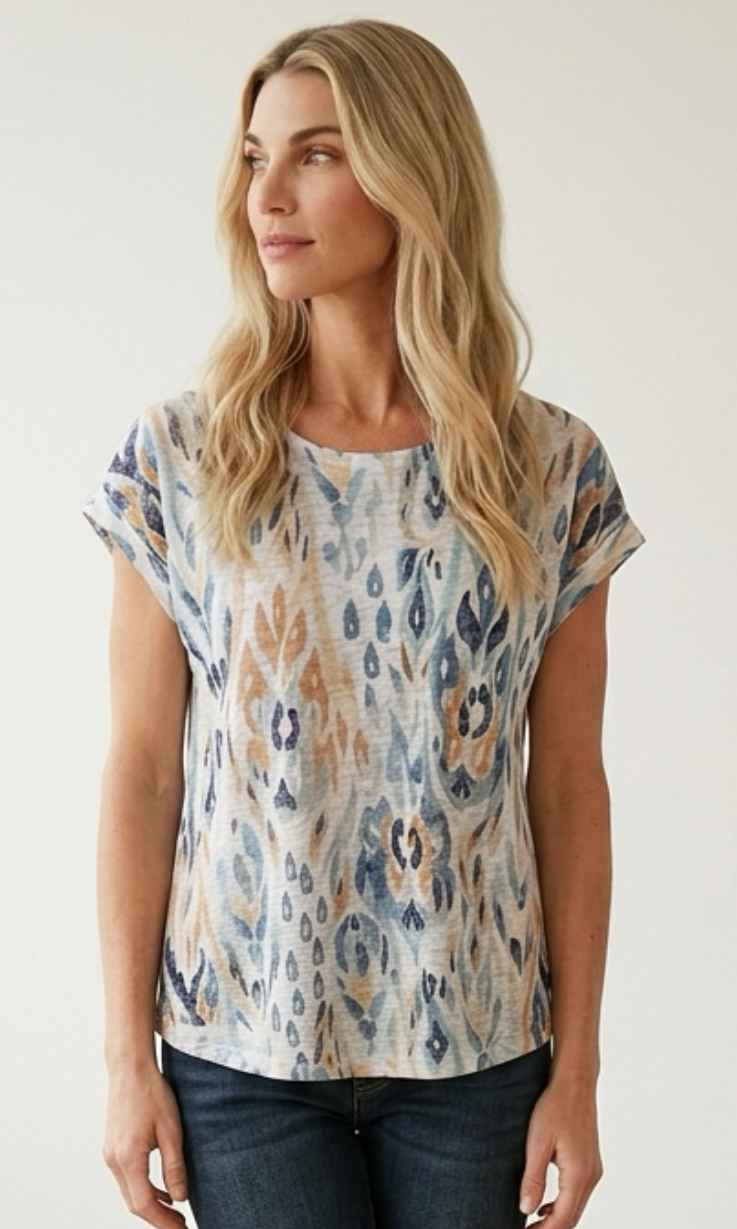 Woman wearing a patterned top and jeans against a plain background