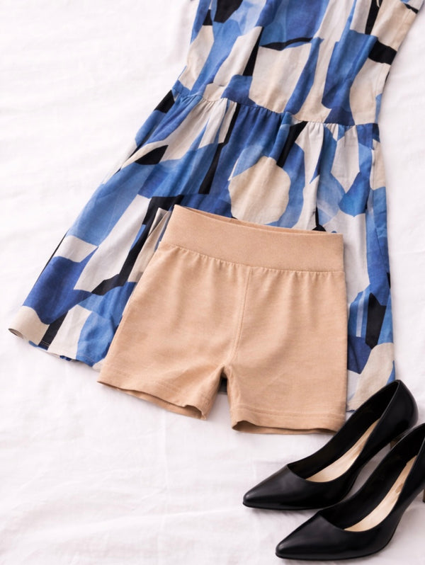 Beige shorts with a patterned dress and black shoes on a white background