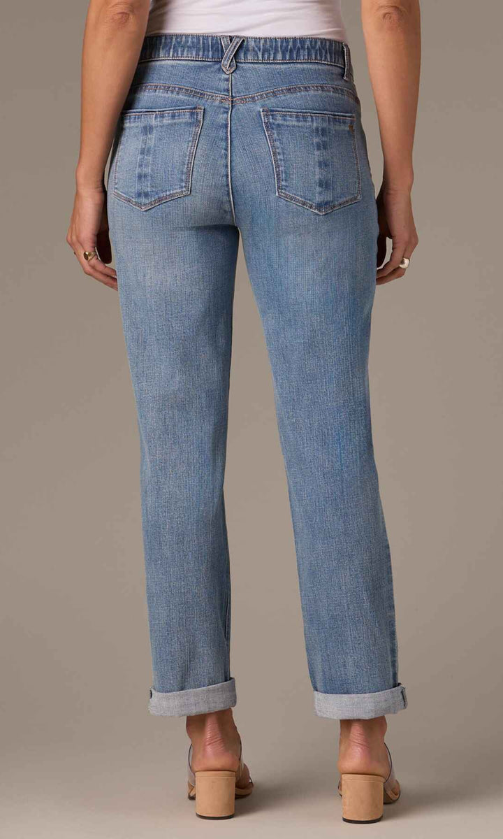 Back view of a person wearing light blue jeans on a neutral background