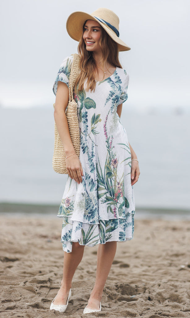 Woman in a floral dress and sun hat on a beach