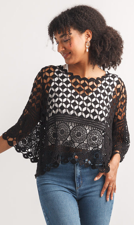 Woman wearing a black lace top and blue jeans on a white background
