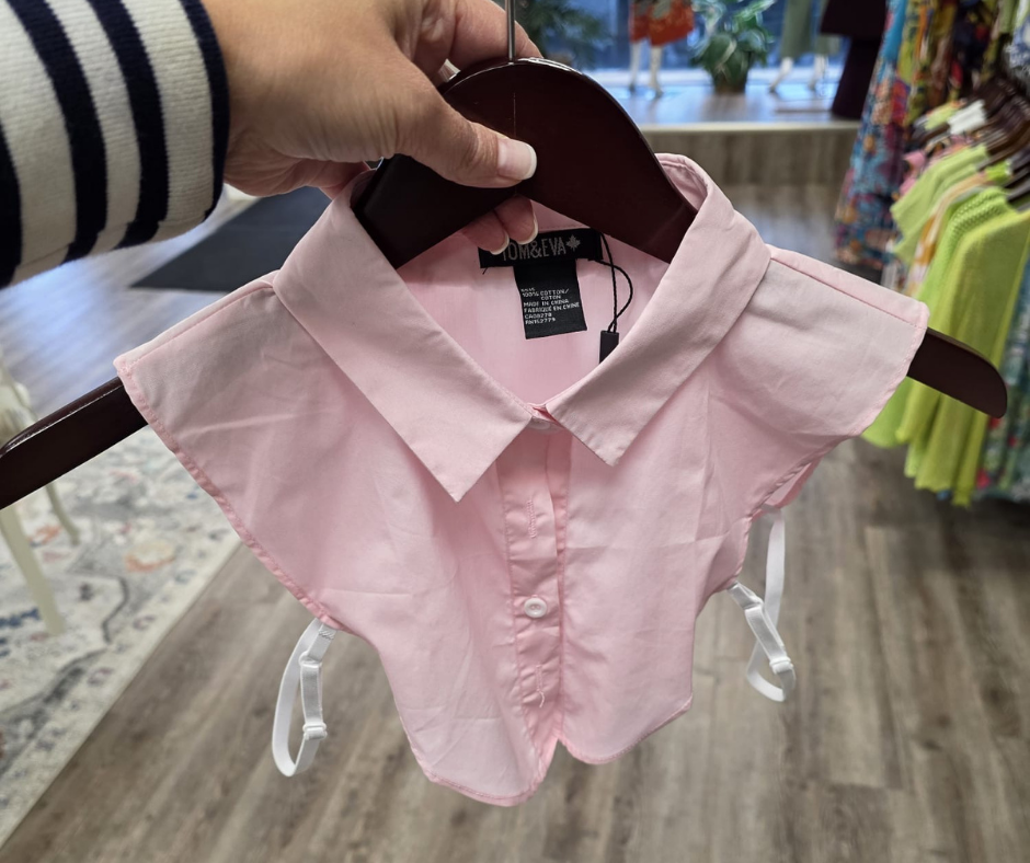 Pink shirt on a hanger with a blurred background of a store interior.