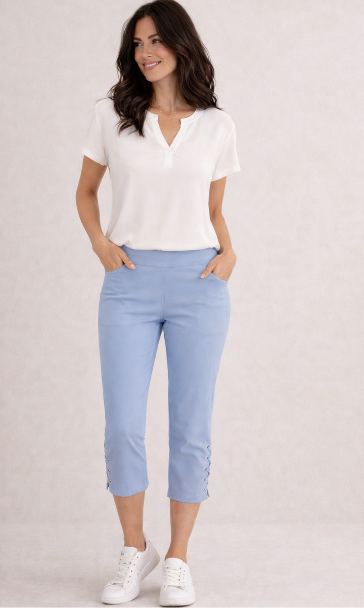 Woman wearing a white blouse and light blue pants on a plain background